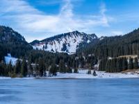 Gefrorener Spitzingsee mit Bodenschneid dahinter